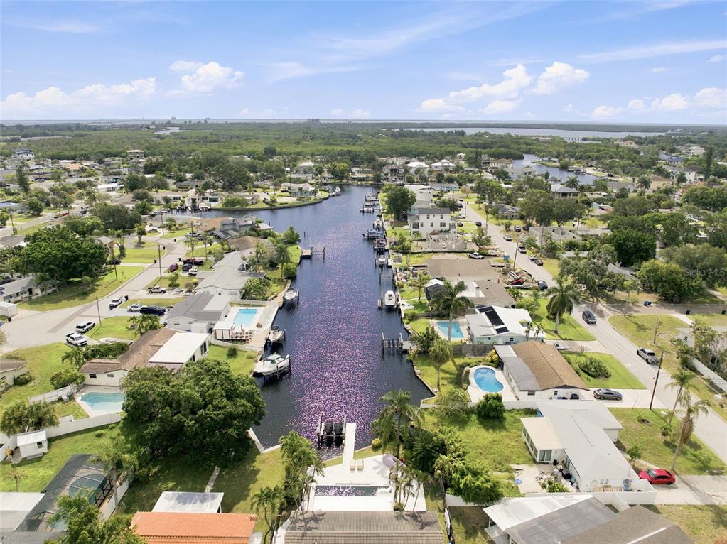 An aerial view shows a canal lined with residential houses, swimming pools, and private docks — 101 92ND AVENUE N, ST PETERSBURG, FL