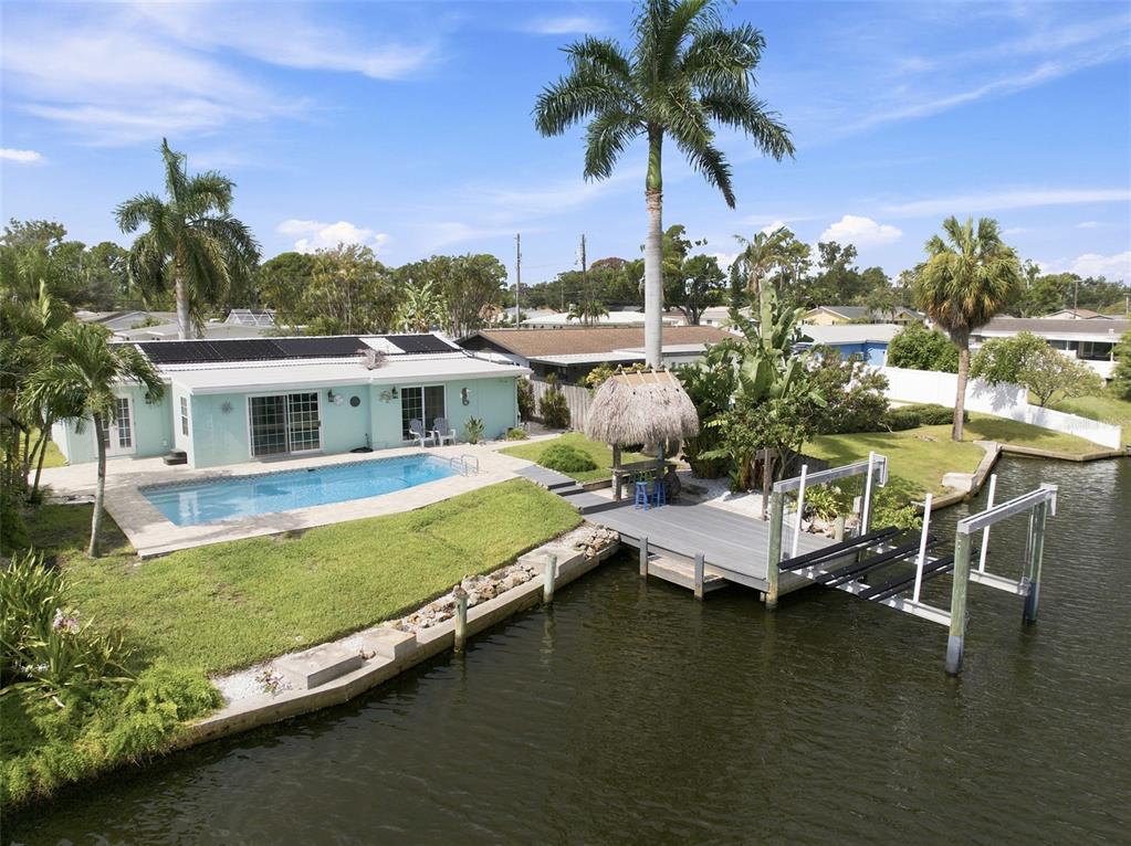 An aerial view of a waterfront home featuring a swimming pool, dock, and tiki hut — 101 92ND AVENUE N, ST PETERSBURG, FL