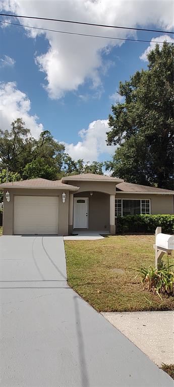A single-story house with a beige exterior, a one-car garage, and a white front door — 3103 E 25TH AVENUE, TAMPA, FL