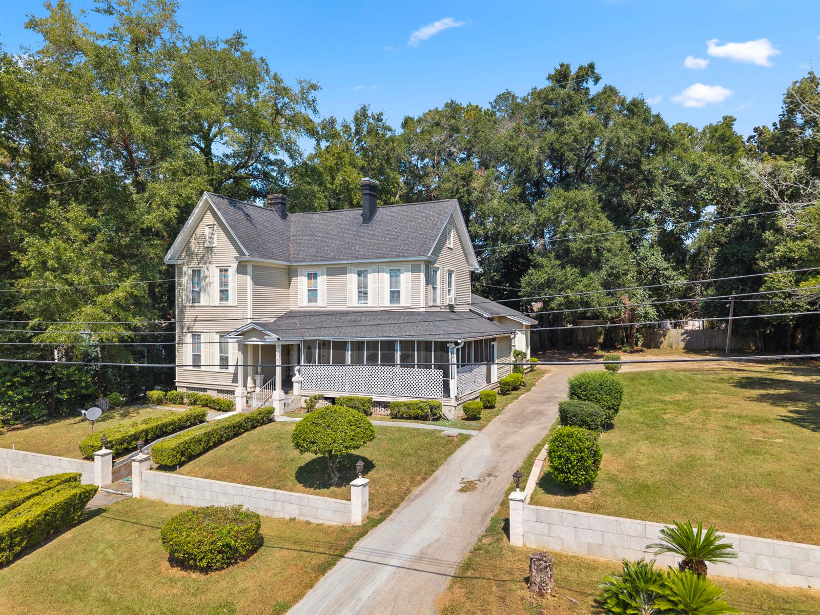 An aerial view of a two-story beige house with a wrap-around porch and driveway — 618 W Washington Street, FL 32351, FL