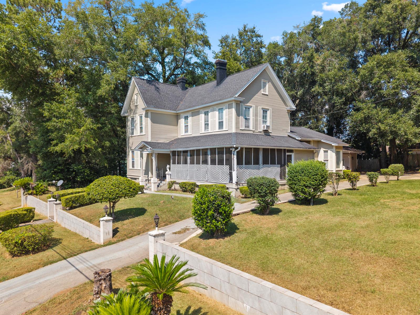 An exterior view of a two-story house with light siding, a screened porch, and landscaping — 618 W Washington Street, FL 32351, FL