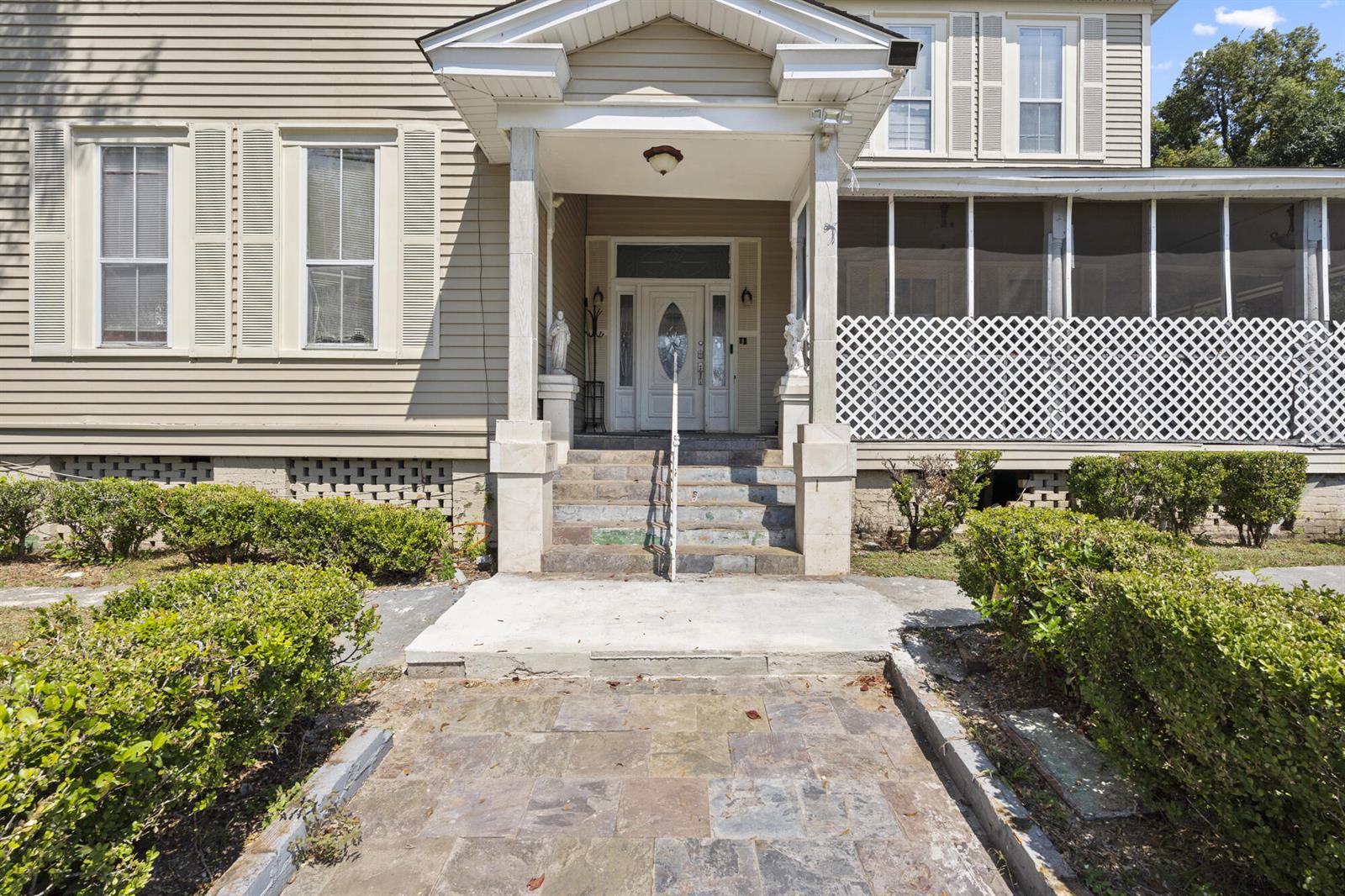 The exterior of a house features a covered front porch, stone steps, and landscaping — 618 W Washington Street, FL 32351, FL