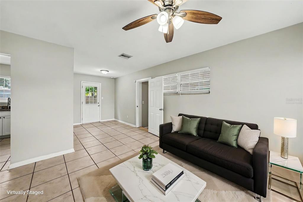 A living room with light tile floors, a ceiling fan, and a dark sofa — 10209 N 28TH STREET, TAMPA, FL