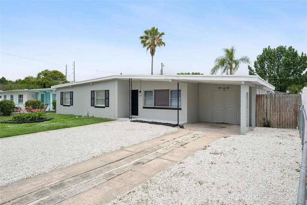 A single-story house with a gray exterior, a gravel driveway, and an attached carport — 7019 ALVINA WAY, ORLANDO, FL