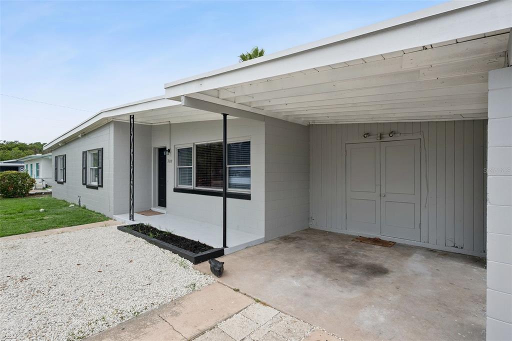 A gray, single-story house features a covered carport with double doors and a front porch — 7019 ALVINA WAY, ORLANDO, FL