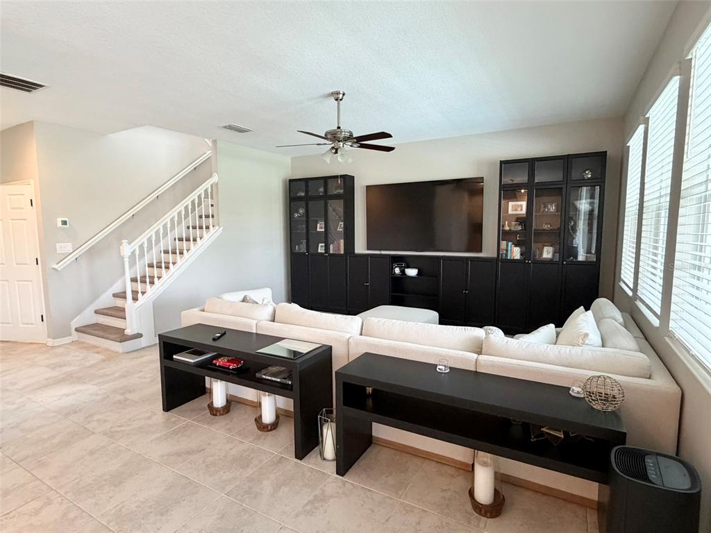 A living room features a large white sectional sofa, black media cabinetry, and a staircase — 1659 CHATSWORTH CIRCLE, ST CLOUD, FL
