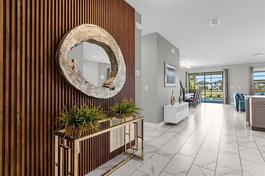 An entryway features a wood-slat accent wall, a circular mirror, and a gold console table — 2931 FABLE STREET, KISSIMMEE, FL