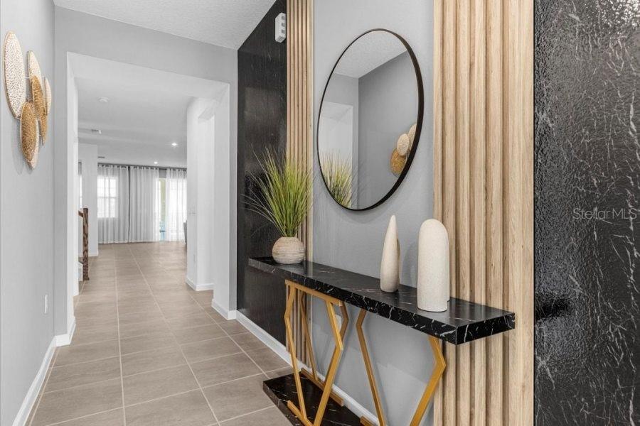 A modern entryway features a black marble console table, a round mirror, and wood slat accents — 9139 TURQUOISE WAVE COVE, KISSIMMEE, FL