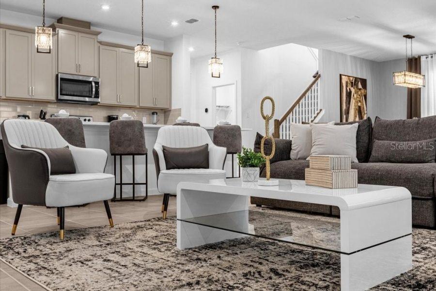 A modern open-concept living room and kitchen featuring neutral tones, contemporary furniture, and pendant lighting — 9139 TURQUOISE WAVE COVE, KISSIMMEE, FL