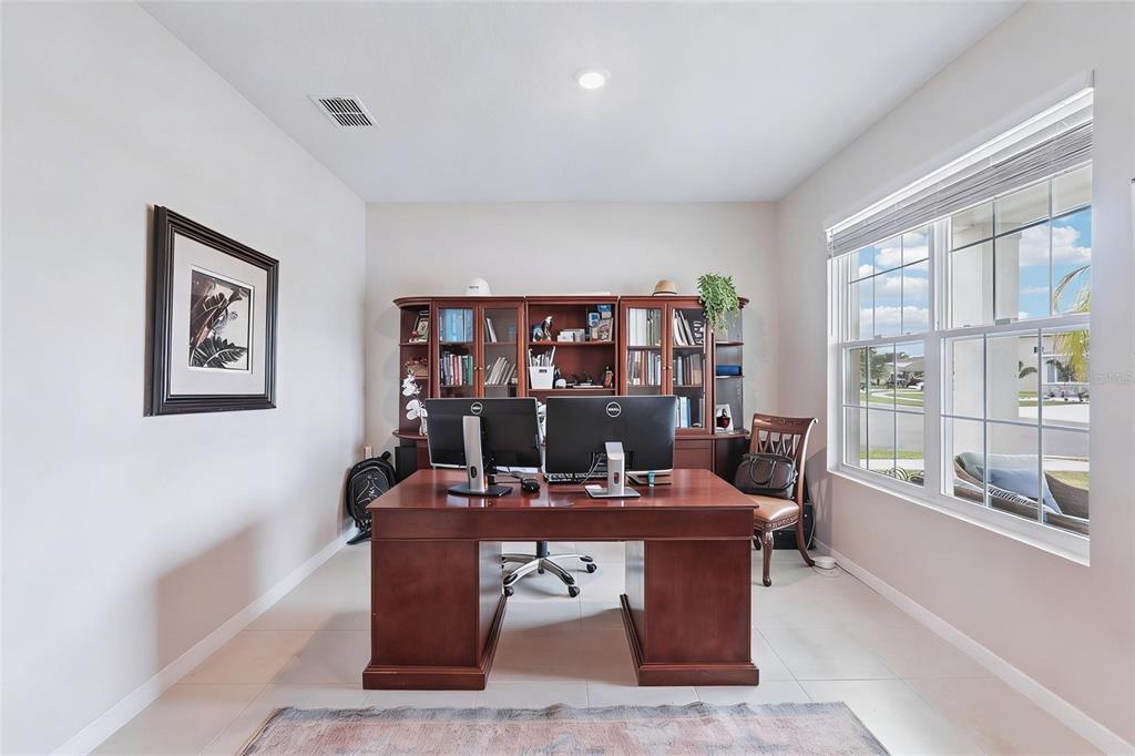 A home office features a large wooden desk, dual monitors, and a matching bookshelf — 13055 WILLOW GROVE DRIVE, RIVERVIEW, FL