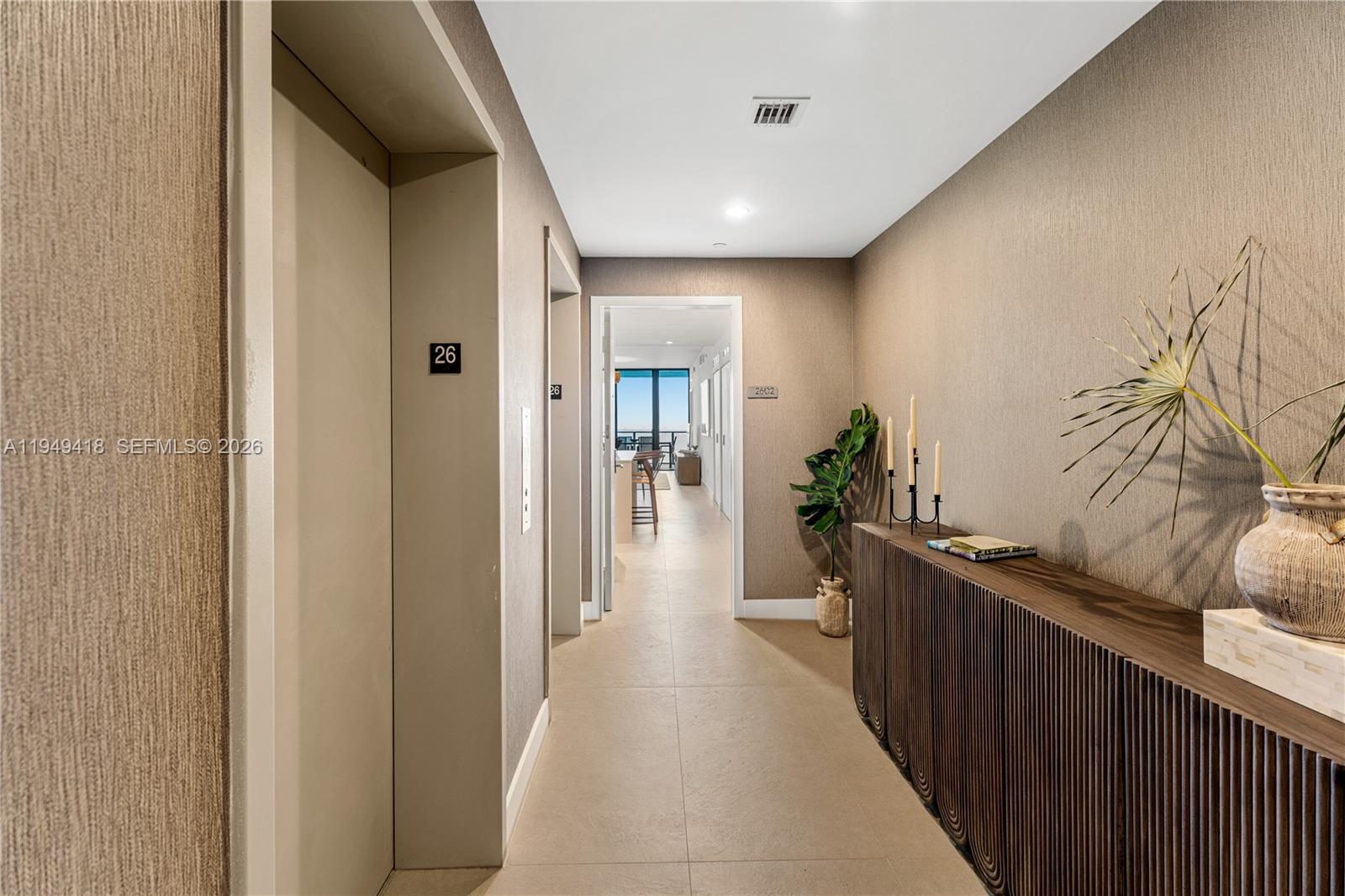 A hallway with an elevator, a console table, and a view into an apartment unit — 700 NE 24th St # 2602, Miami FL 33137, MIAMI, FL