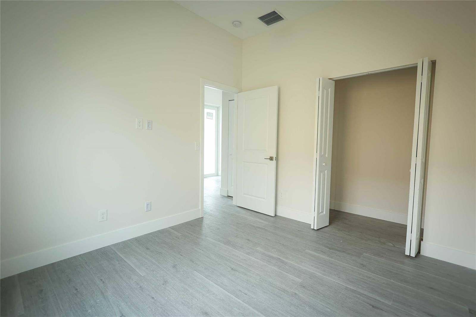 A bedroom with light-colored walls, gray wood-look flooring, a closet, and an open doorway — 732 19th Street, West Palm Beach FL 33407, WEST PALM BEACH, FL