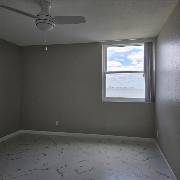 An empty bedroom features gray walls, white marble-patterned tile flooring, a ceiling fan, and a window — 4015 BAYSHORE BOULEVARD UNIT 7F, TAMPA, FL
