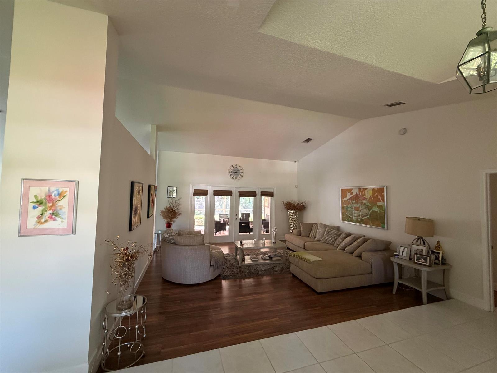 A spacious living room features vaulted ceilings, hardwood floors, a sectional sofa, and glass doors — 1770 Emilio Lane, Palm Springs FL 33406, PALM SPRINGS, FL
