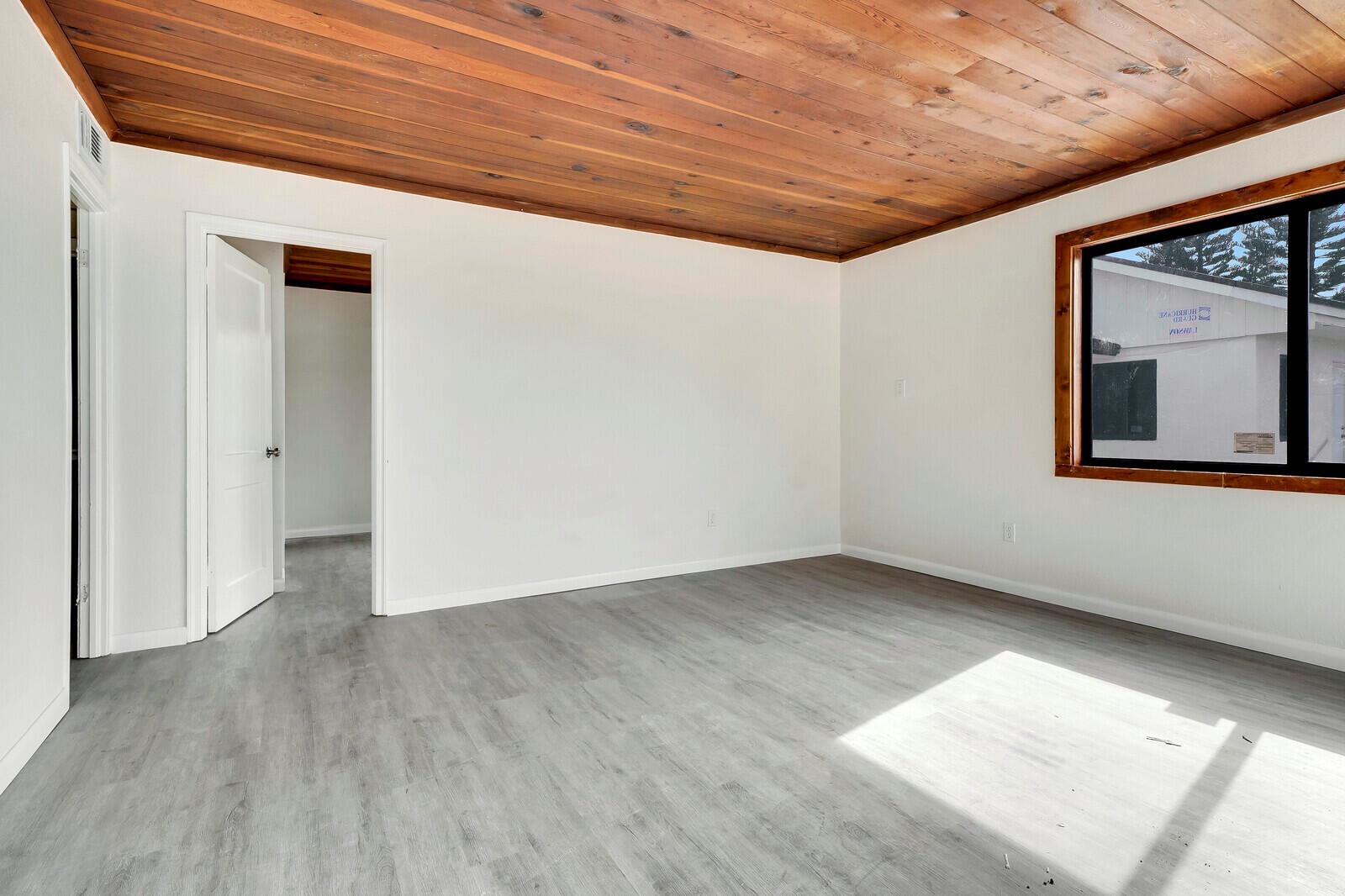 An empty bedroom features white walls, gray wood-look flooring, and a natural wood plank ceiling — 652 Hernando Street # C, Fort Pierce FL 34949, FORT PIERCE, FL
