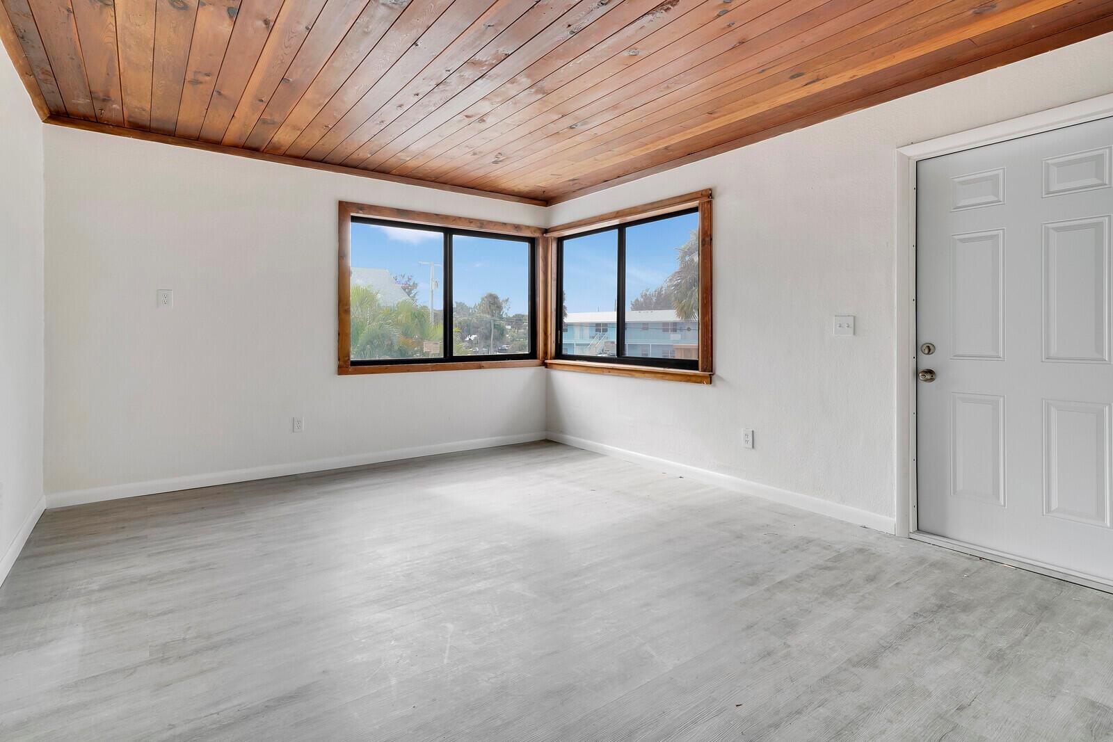 An empty room features light wood-look flooring, white walls, and a natural wood plank ceiling — 652 Hernando Street # C, Fort Pierce FL 34949, FORT PIERCE, FL