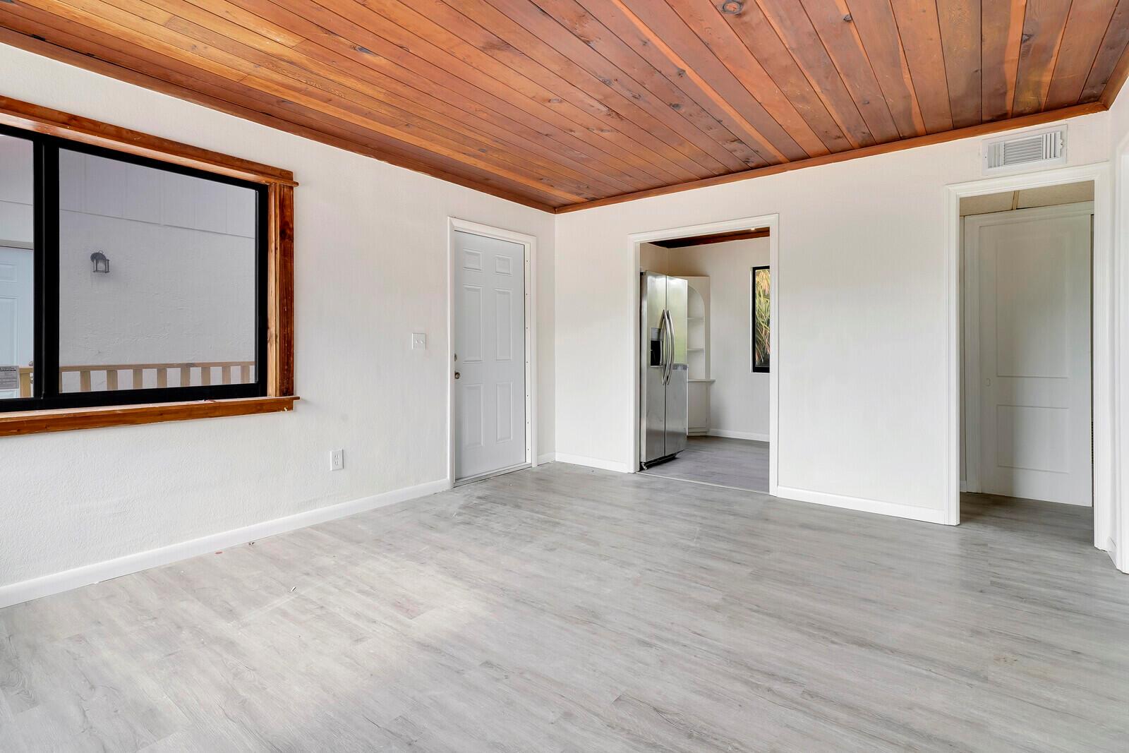 An empty room features light gray wood-look flooring, white walls, and a wood-paneled ceiling — 652 Hernando Street # C, Fort Pierce FL 34949, FORT PIERCE, FL