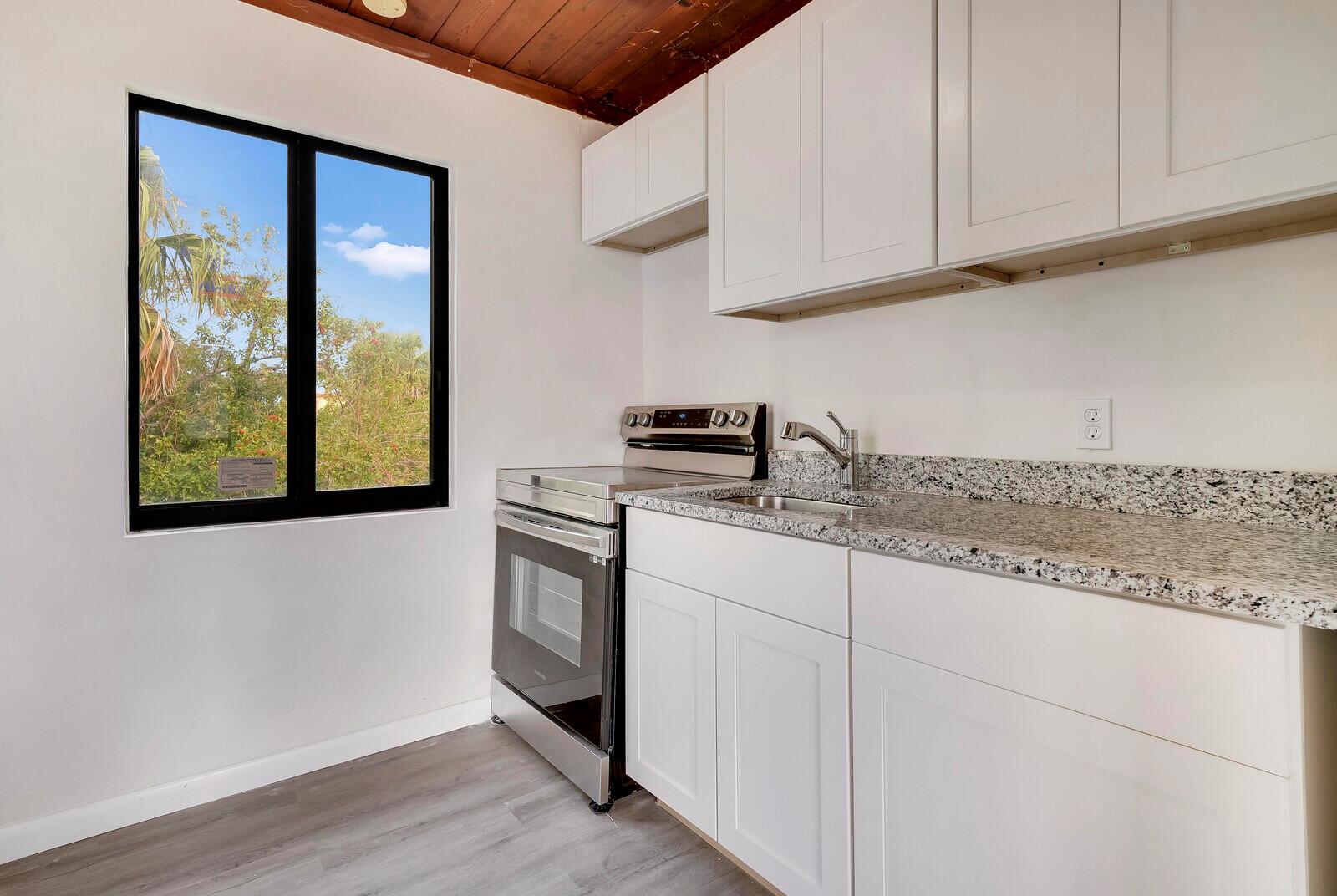 A kitchen features white cabinets, granite countertops, stainless steel appliances, and a wood-paneled ceiling — 652 Hernando Street # C, Fort Pierce FL 34949, FORT PIERCE, FL