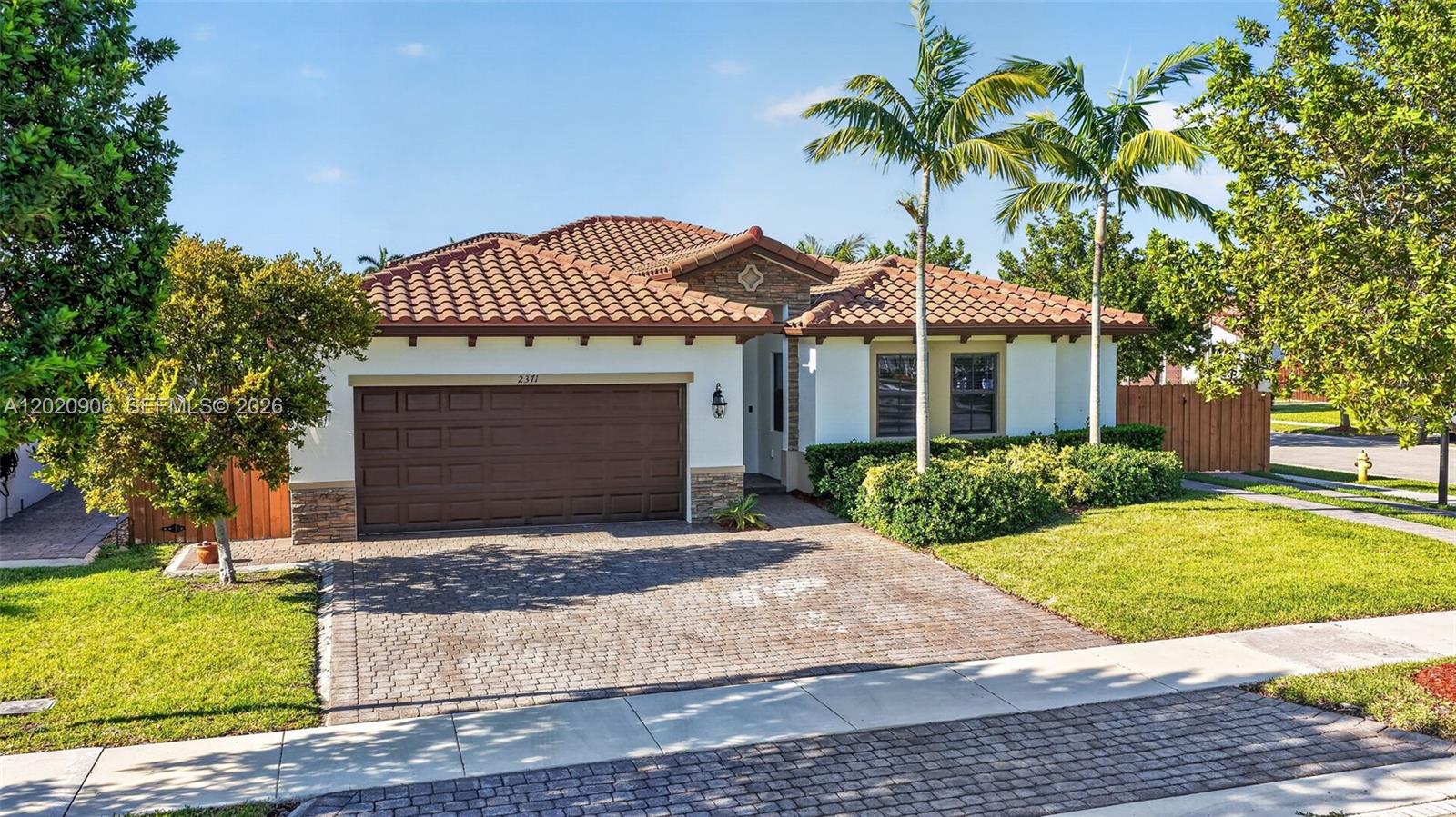 A single-story house with a brown garage door, tiled roof, and a brick paver driveway — 2371 SE 1st Ct, Homestead FL 33033, HOMESTEAD, FL