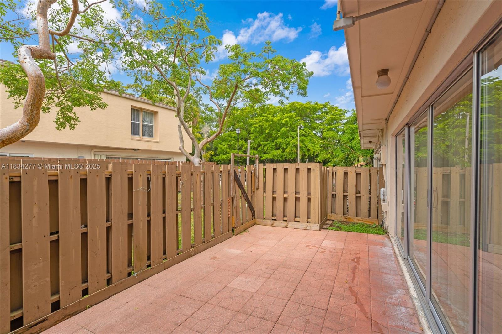 A paved patio area features a wooden privacy fence and sliding glass doors — 8256 NW 9th Ct # 2, Plantation FL 33324, PLANTATION, FL