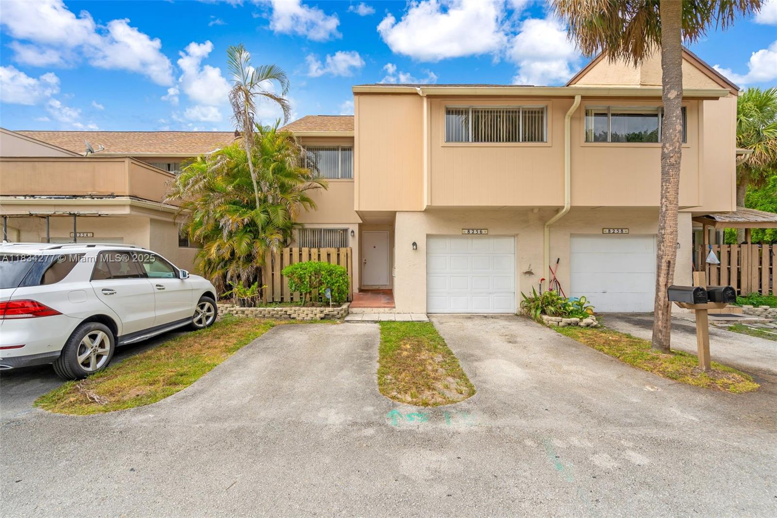 A two-story townhouse exterior features a white garage, a driveway, and a palm tree — 8256 NW 9th Ct # 2, Plantation FL 33324, PLANTATION, FL