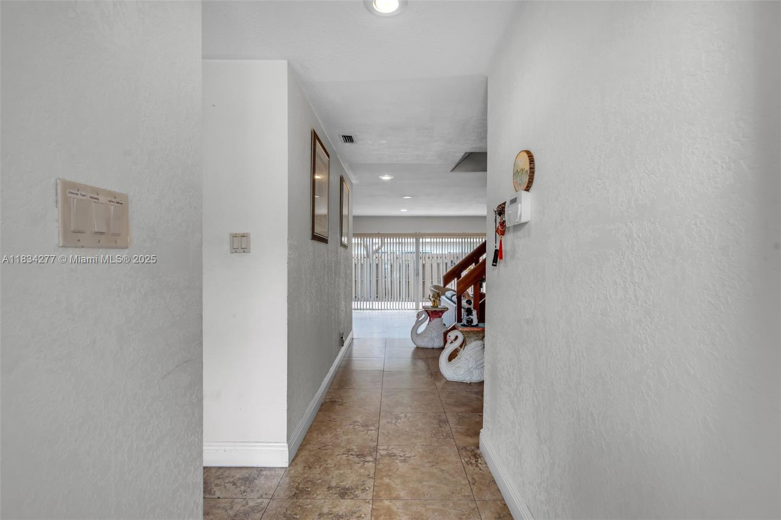 A tiled hallway leads toward a living area with a staircase and swan statues — 8256 NW 9th Ct # 2, Plantation FL 33324, PLANTATION, FL