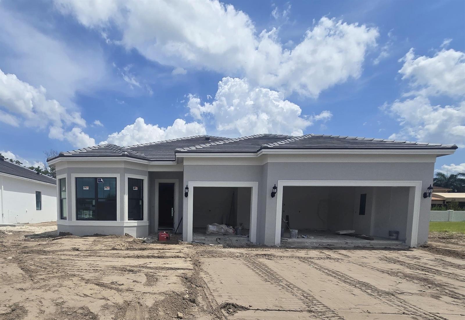 A newly constructed single-story house with a gray stucco exterior and a three-car garage — 9604 Galata Tower Lane, Lake Worth FL 33467, LAKE WORTH, FL