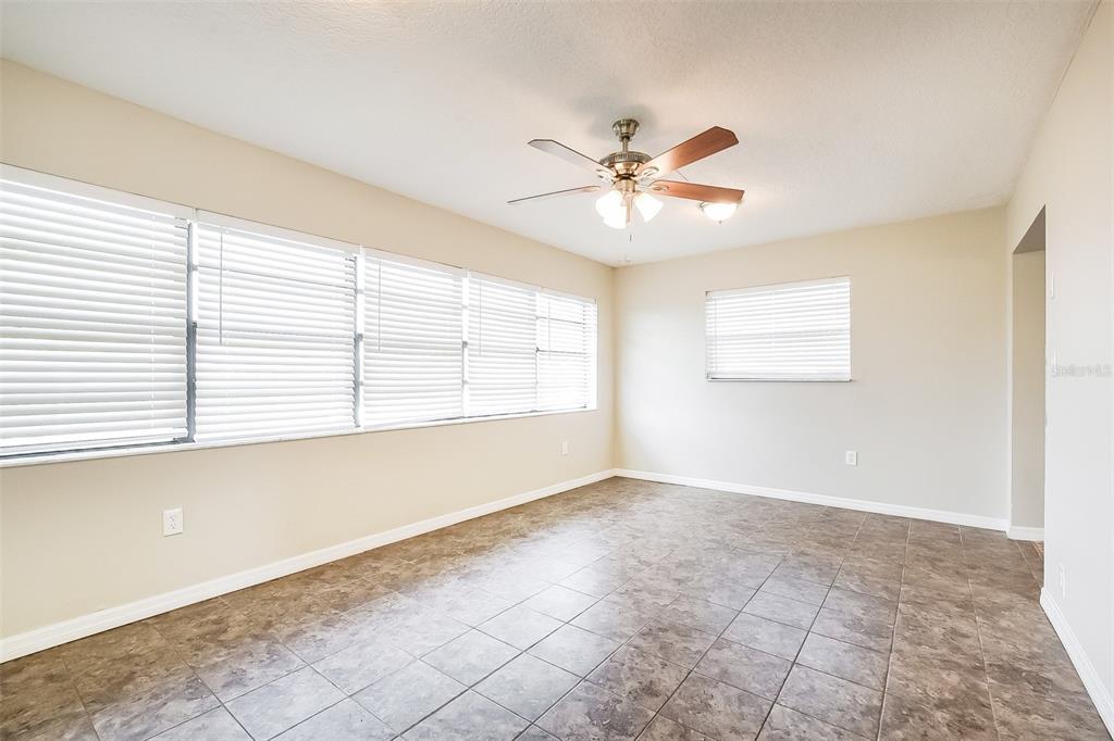An empty room with tiled floors, a ceiling fan, and multiple windows with white blinds — 2072 DUMAS DRIVE, DELTONA, FL