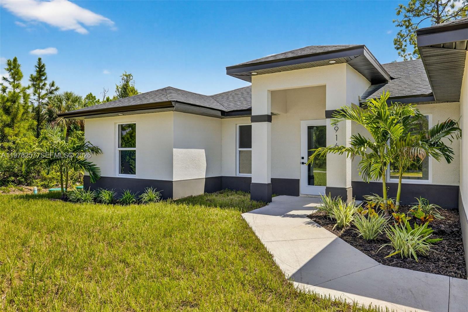 A modern single-story house with a white stucco facade, dark trim, and a front walkway — 2916 Dora, Lehigh Acres FL 33974, LEHIGH ACRES, FL