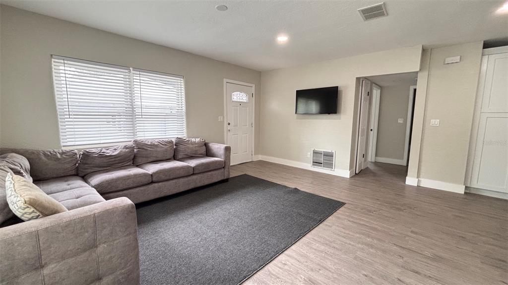 A living room features gray flooring, a sectional sofa, a coffee table, and white cabinets — 2816 HARGILL DRIVE, ORLANDO, FL