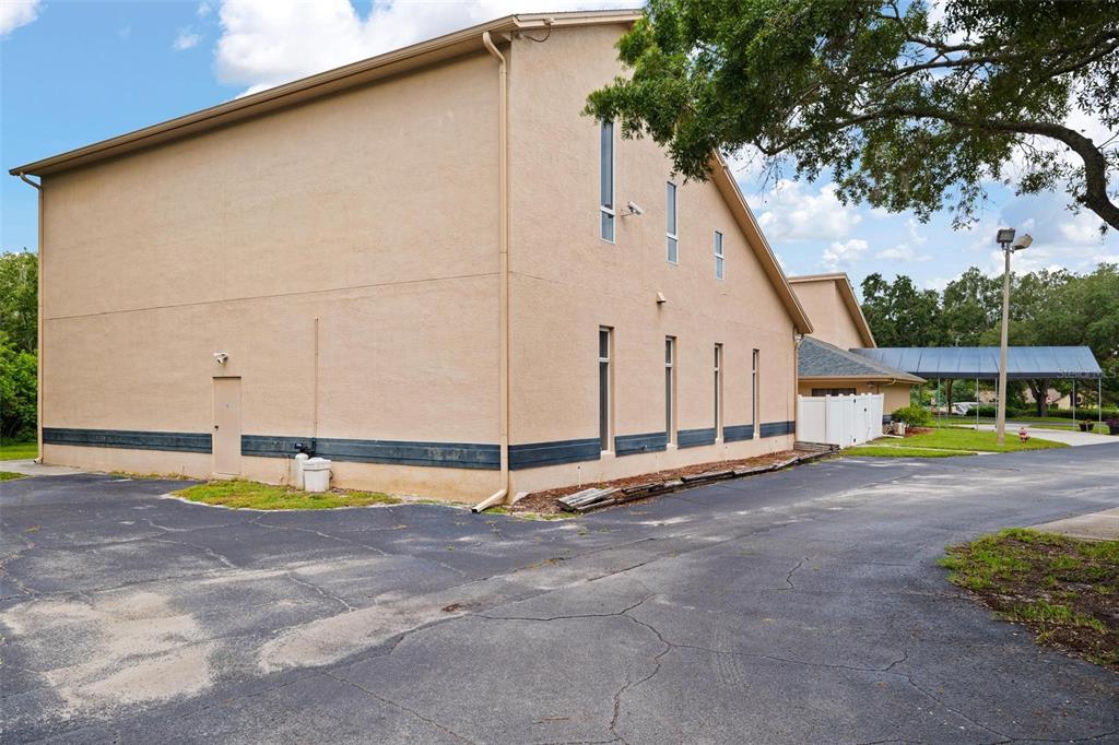 The exterior of a beige building features a paved parking lot and a covered walkway — 3730 TAMPA ROAD UNIT 3730-B, PALM HARBOR, FL