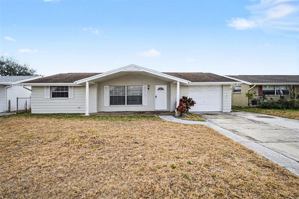 A single-story house with a light-colored brick facade, a front porch, and an attached garage — 7224 INGLESIDE DRIVE, PORT RICHEY, FL