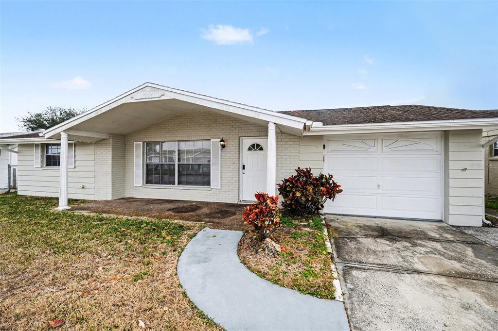 A single-story house with a white brick facade, a covered porch, and an attached garage — 7224 INGLESIDE DRIVE, PORT RICHEY, FL