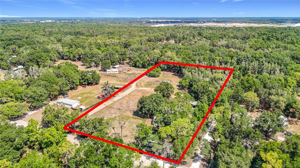 An aerial view shows a rectangular plot of land outlined in red amidst wooded surroundings — 40949 JERRY ROAD, ZEPHYRHILLS, FL