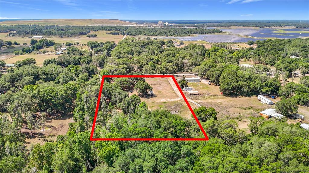 An aerial view shows a rectangular plot of land outlined in red amidst wooded surroundings — 40949 JERRY ROAD, ZEPHYRHILLS, FL