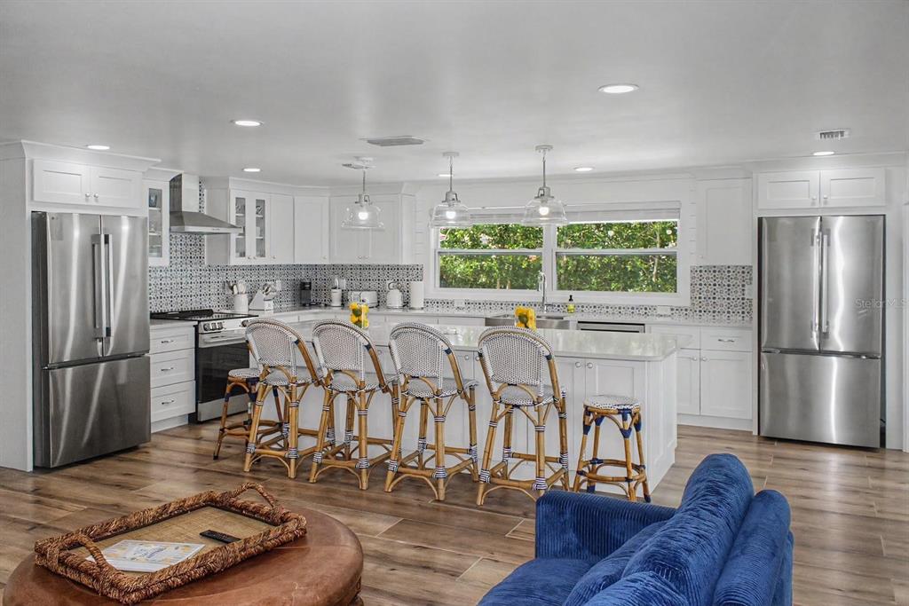 A bright kitchen features white cabinetry, stainless steel appliances, a large island, and bar stools — 6927 21ST STREET W, BRADENTON, FL