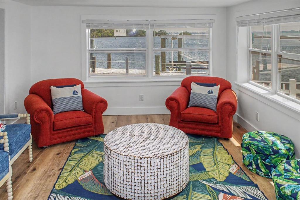 A living area features two red armchairs, a patterned rug, and windows overlooking a dock — 6927 21ST STREET W, BRADENTON, FL