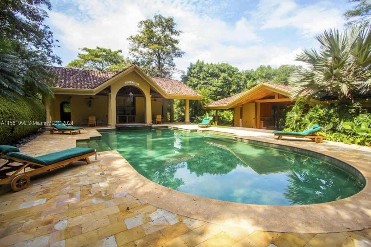 A swimming pool sits on a stone patio between two open-air structures with tiled roofs — 9 Santa Rita de OROTINA Casa de Campo Costa Rica., Al, Al