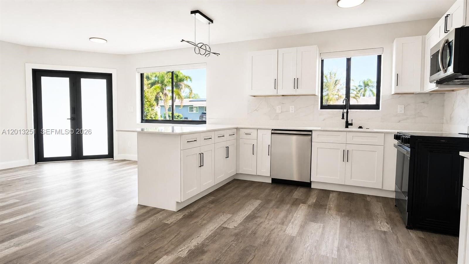 A modern kitchen features white cabinets, stainless steel appliances, and wood-look flooring — 7181 Raleigh St, Hollywood FL 33024, HOLLYWOOD, FL