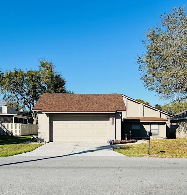 A single-story house with a large garage and a brown shingled roof under a blue sky — 1422 SPALDING ROAD, WINTER SPRINGS, FL