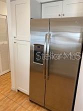 A stainless steel side-by-side refrigerator is positioned next to white cabinets in a kitchen — 1422 SPALDING ROAD, WINTER SPRINGS, FL
