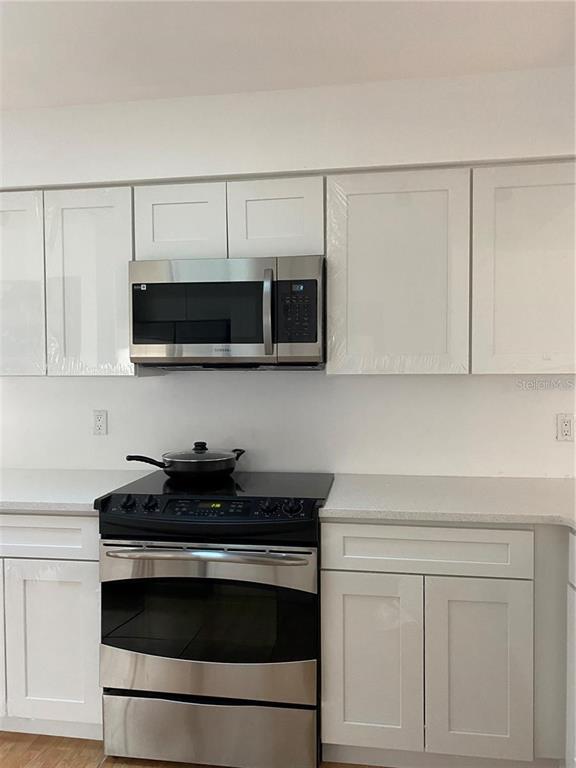 A kitchen features white shaker cabinets, stainless steel appliances, and light-colored countertops — 1422 SPALDING ROAD, WINTER SPRINGS, FL