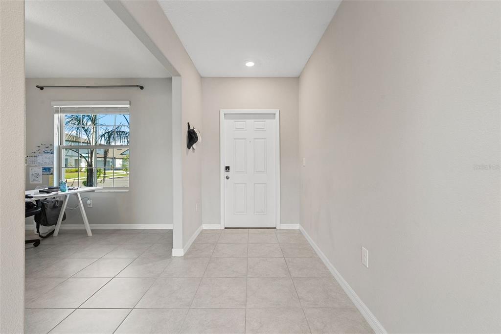 An entryway with light tile flooring leads to a white front door and adjacent office space — 5553 TURKEY CREEK WAY, LAKELAND, FL