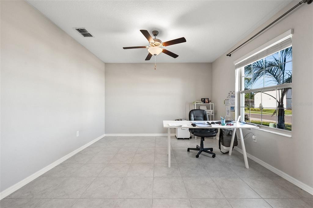 A home office features light-colored tile flooring, a ceiling fan, and a desk by a window — 5553 TURKEY CREEK WAY, LAKELAND, FL