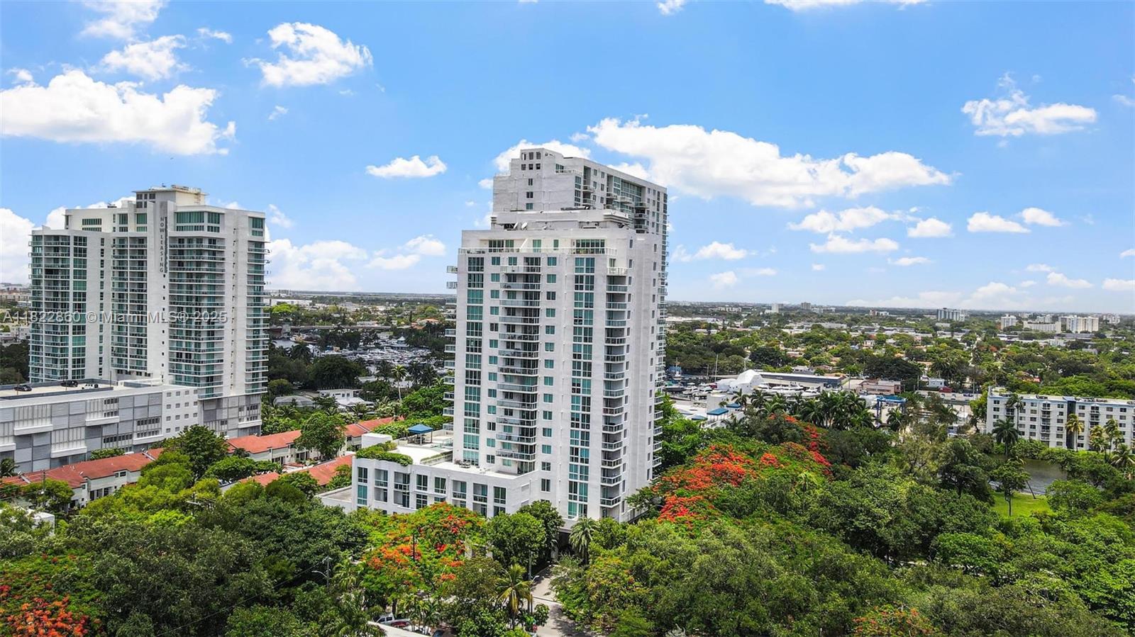 An aerial view shows two tall residential buildings surrounded by lush green trees and vegetation — 1861 NW S River Dr # 01, Miami FL 33125, MIAMI, FL