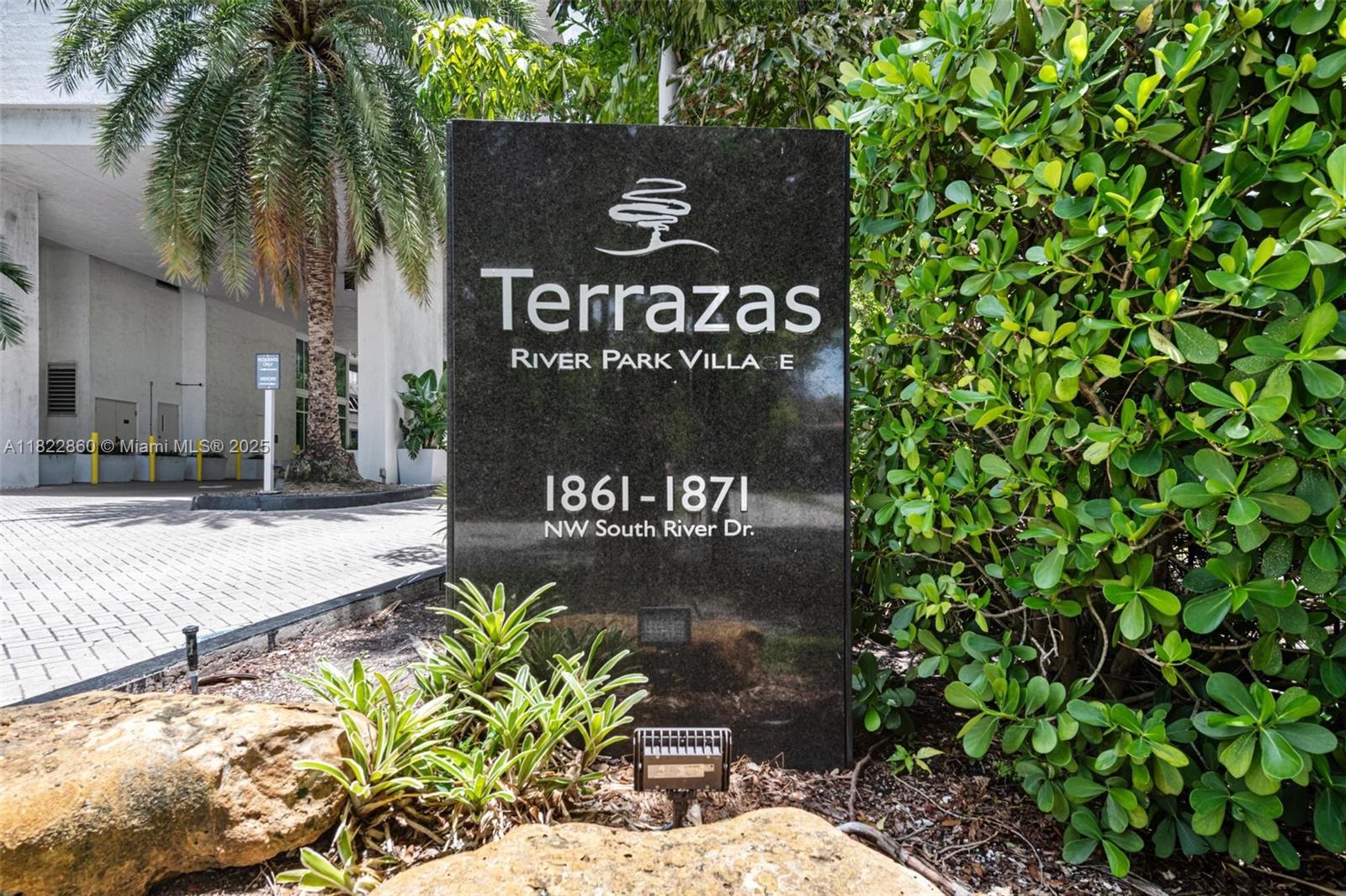 A black stone monument sign stands in front of a building with palm trees — 1861 NW S River Dr # 01, Miami FL 33125, MIAMI, FL