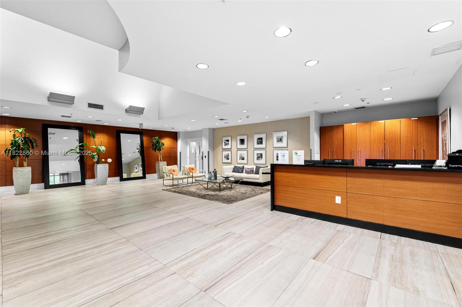 A modern lobby features a wooden reception desk, tile flooring, and a seating area — 1861 NW S River Dr # 01, Miami FL 33125, MIAMI, FL