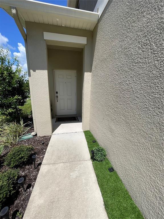 A concrete walkway leads to a white front door under a covered entryway — 15246 HARRINGTON COVE DRIVE, ORLANDO, FL