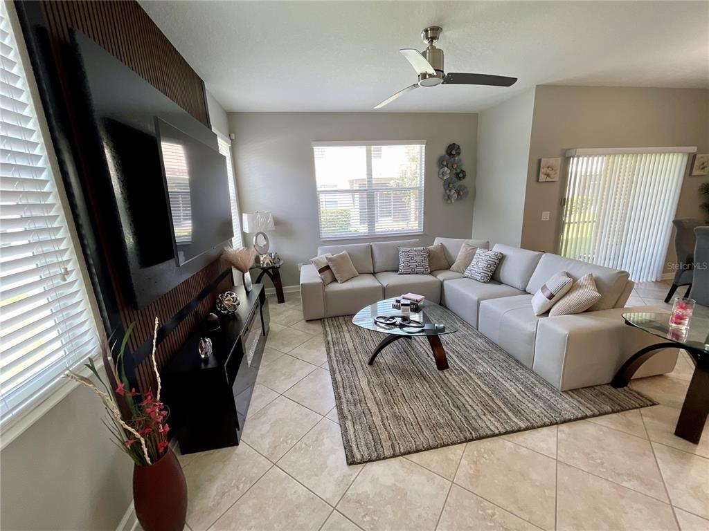A living room features a large sectional sofa, a wall-mounted television, and tile flooring — 15246 HARRINGTON COVE DRIVE, ORLANDO, FL