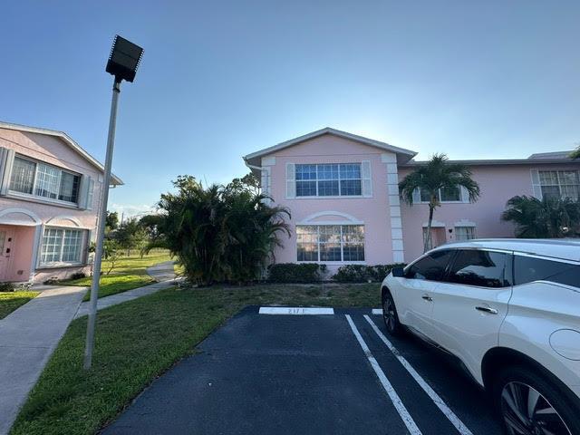A white SUV is parked in front of a two-story pink residential building — 217 Foxtail Drive # H, FL 33415, FL